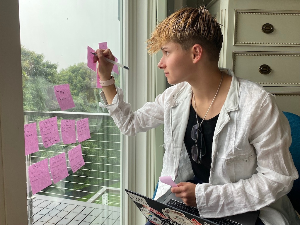 Maria Angelini making a note on a post-it stuck to a window as she looks outside